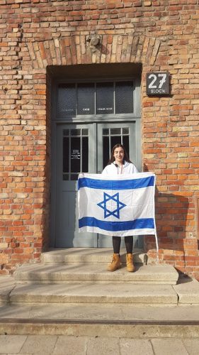 טל אנגל עם דגל ישראל ליד בלוק 27 באושוויץ