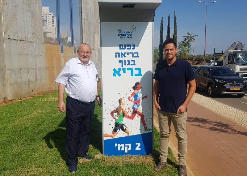 משמאל: רחמים מלול ויניב מרקוביץ׳ ליד שלט סימון מרחק בציר מנחם בגין